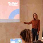 Young woman presenting on digital evolution concepts like AI and big data in a seminar., tags: skillsoft - pexel