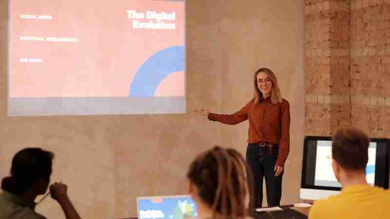 Young woman presenting on digital evolution concepts like AI and big data in a seminar., tags: skillsoft - pexel